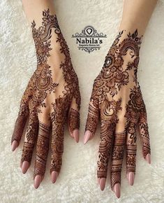 two hands with henna tattoos on them, one is showing off the intricate design