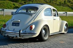 an old vw bug is parked on the side of the road with grass in the background