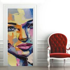 an open door with a painting of a woman's face on it and a red chair next to it