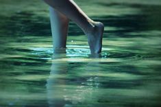 a person standing in the water with their feet up