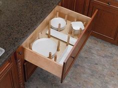 an open drawer in the middle of a kitchen counter with plates and bowls on it