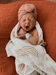 a baby wrapped in a blanket is yawning