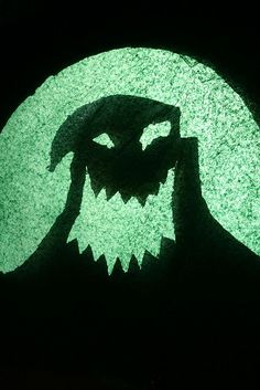 the shadow of a person's face in front of a green circle with an image of a monster on it