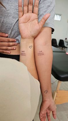 two people with matching tattoos on their arms and one is holding the other's hand