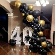 the balloon arch is decorated with black, gold and white balloons that spell out 40