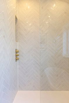 a shower with white tile and gold fixtures