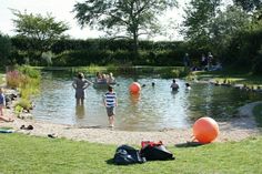 several people are playing in the water with large orange balls and backpacks on the shore