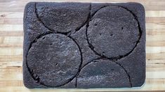 a square shaped chocolate cake sitting on top of a wooden cutting board