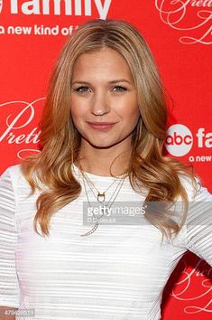 a beautiful blonde woman posing for the camera on a red carpet with her hands on her hips