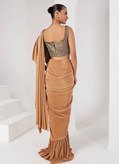 This elegant Gold Pre-Draped Lycra Saree Set, crafted from a luxurious blend of lycra and crepe, exudes timeless sophistication. The fluid draping of the gold saree, enhanced by the rich texture of the fabrics, makes it a standout choice for any special occasion. Paired with a striking grey blouse, intricately hand-embellished to add a touch of glamour, this ensemble is perfect for festive celebrations or sangeet ceremonies. Composition : Blouse - Crepe blend & Saree - Crushed Lycra Saree Care: Dry Clean Only and Vacuum Storage This product can be customized for sleeves, blouse length and neckline Delivery : 2-4 weeks as the product is hand crafted. Check Size Guide or choose MySize for free customisation (All Sizes above XL can be made at 15% additional cost) For more information and size Elegant Floor-length Pre-draped Saree With Unstitched Blouse, Fitted Gold Pre-draped Saree For Festive Occasions, Elegant Saree-style Draped Skirt For Party, Elegant Party Draped Saree Skirt, Fitted Sets With Traditional Drape In Elegant Style, Elegant Pre-draped Saree With Zari Work, Fitted Raw Silk Saree For Reception, Elegant Draped Skirt For Festive Evening, Elegant Draped Skirt For Evening Festivities