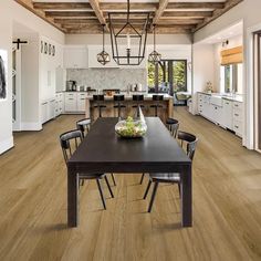 a dining room table and chairs in front of an open kitchen with wood flooring