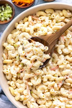 a bowl filled with macaroni salad and a wooden spoon on top of it