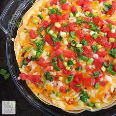 a pizza with lots of toppings in a glass pie dish on a black surface