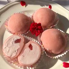 three desserts on a white plate with red flowers and petals in the background for decoration