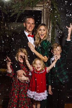 a group of people standing next to each other in front of a mirror with snow falling on them