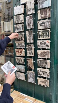 a woman pointing at pictures on a wall in front of a book store with people looking at them