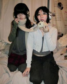 two young women sitting on a bed with stuffed animals in their hands and one holding a teddy bear