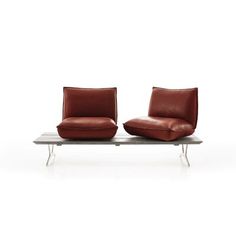 two red leather chairs sitting next to each other on a metal table with white background