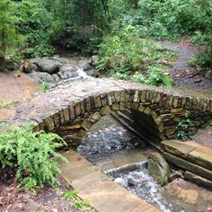 a stone bridge over a stream in the woods