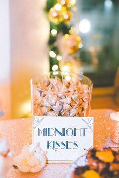 a table topped with a glass bowl filled with food next to a sign that says midnight kisses