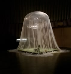 a large white object covered in plastic on top of a black floor next to a building