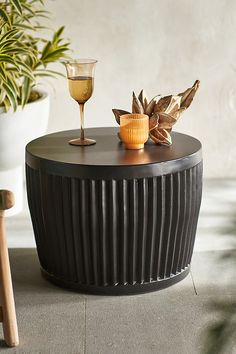 a glass of wine sitting on top of a table next to a potted plant