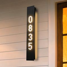 a house number sign is lit up on the side of a building with two windows