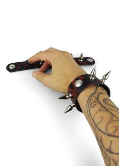 These cuffs with spikes have a punk wristband feel to them. Made from leather, each spiked cuff has a red skull and crossbones print randomly arranged across the black surface. This pirate symbolism, with its connotations of rebellion, makes these studded wristbands a great alternative to more traditional biker bracelets. This pair of leather spiked cuffs also make for good clubwear accessories to give both male and female alternative outfits an extra edge. If you're dressed in black gothic atti Biker Bracelet, Leather Wrist Cuff, Dark Street, Anti Fashion, Punk Inspiration, Red Skull, Classic Wardrobe, Wrist Cuffs, Skull And Crossbones