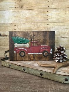 an old red truck with a christmas tree on it is sitting on a wooden tray