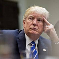 a man in a suit and tie sitting at a table with his hand on his head