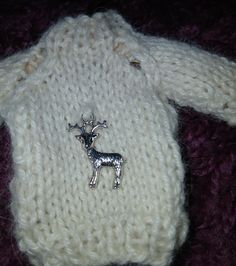 a knitted sweater with a deer brooch on it