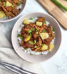 two bowls filled with food on top of white rice