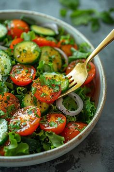 a salad with cucumbers, tomatoes, onions and herbs in a white bowl