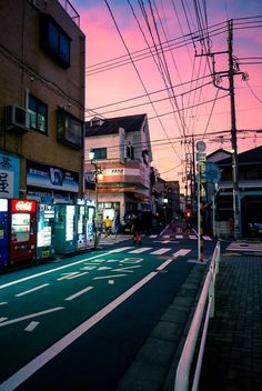 an empty city street at dusk with power lines above the road and buildings in the background