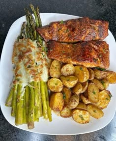 a white plate topped with meat, potatoes and asparagus