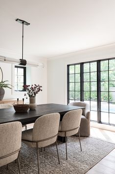 the dining room table is surrounded by beige chairs and black tables with gray upholstered chairs