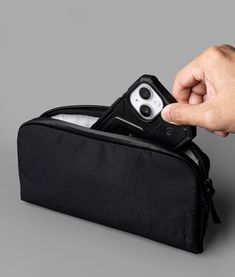 a hand holding an electronic device in a black case