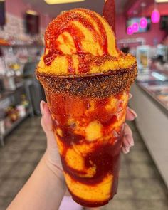 a person holding up an ice cream sundae in a store filled with confections