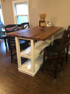 a kitchen table with two stools next to it on a hard wood flooring