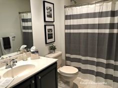 a white toilet sitting next to a bathroom sink under a mirror and a shower curtain