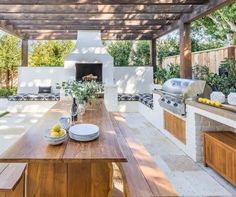 an outdoor kitchen and dining area with wood table, grilling oven, and benches