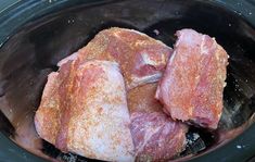 raw meat in a crock pot with seasoning sprinkled on the top