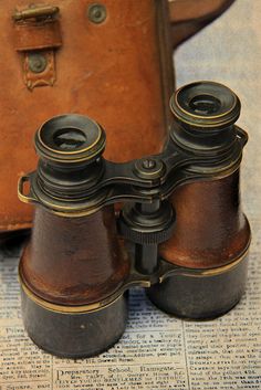 an old pair of binoculars sitting on top of a newspaper