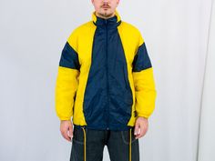 "UNCLE ED PRESENTS - vintage 90's yellow-blue windbreaker - the hood hidden in the collar - 2 outside pockets - lined - material: shell - 100% nylon; lining - 100% cotton. CONDITION (1-10 ❶❷❸❹❺❻❼❽❾ Great condition. SIZE/MEASUREMENTS size from label: M; women 40-42, men 48-50 best fits men: M/L chest: 51 inches (130 cm) length: 30 inches (76 cm) sleeve length from armpit: 18,5 inches (47 cm) The model is 6'1\" (186 cm), measures 41-35-39 (104-88-100 cm) and wears size L" Yellow Hooded Jacket With Pockets For Streetwear, Yellow Hooded Windbreaker For Streetwear, Hooded Yellow Windbreaker For Streetwear, Sporty Yellow Outerwear With Double-lined Hood, Sporty Yellow Hooded Jacket For Streetwear, Retro Yellow Windbreaker For Streetwear, Yellow Retro Windbreaker For Streetwear, Sporty Yellow Hooded Jacket For Outdoor, Yellow Sporty Hooded Jacket For Outdoor