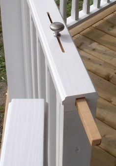 a door handle on the side of a white wooden porch with grass in the background