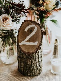 the table is set with vases and flowers in glass jars on which numbers are displayed