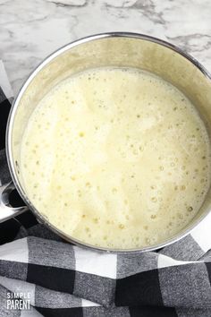 a pot filled with liquid sitting on top of a checkered cloth next to a knife