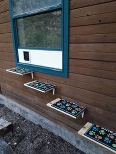 the outside of a house with windows and rugs on the ground next to it