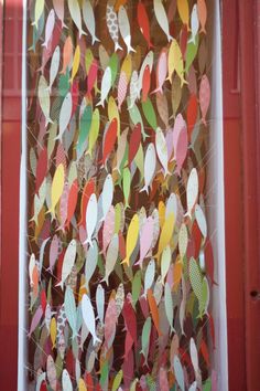 an art project made out of paper leaves on a window sill in front of a red door