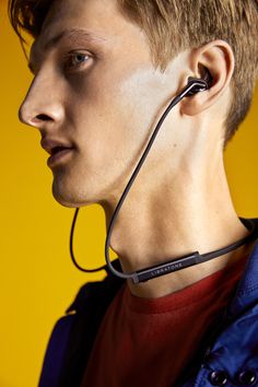 a young man with ear buds on his ears is looking to the side while wearing a blue jacket